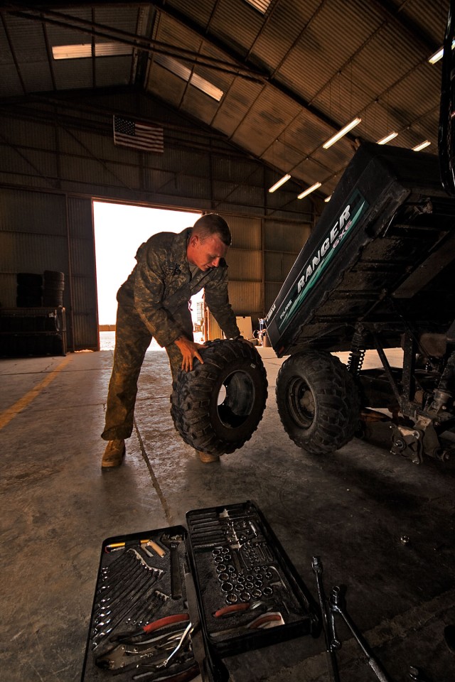 CAMP TAJI, Iraq-After replacing a half shaft, Spc. Brian Frye, from Fredericksburg, Va., a light wheel mechanic in Company E, 4th Battalion, 227th Aviation Regiment, 1st Air Cavalry Brigade, 1st Cavalry Division, begins a tire change on a Polaris,...
