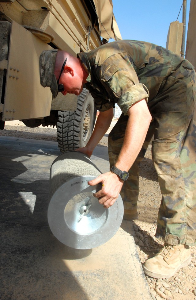 CAMP LIBERTY, Iraq - Sgt. Michael Clark, the quality control and assurance shop foreman, from Arlington, Texas, assigned to Division Special Troops Battalion, 1st Cavalry Division, demonstrates how to remove dust and dirt from an air filter of a...