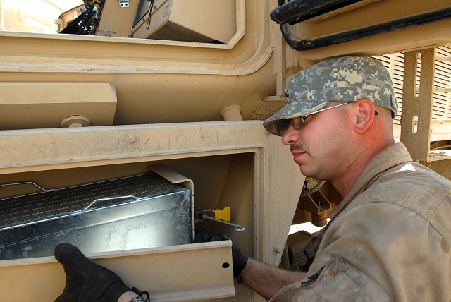 CAMP LIBERTY, Iraq - Spc. Charles Marshall, a light-wheel mechanic, from Wheeling, W.V., assigned to quality control, Division Special Troops Battalion, 1st Cavalry Division, takes out a protective plate of armor in order to remove the air filter...