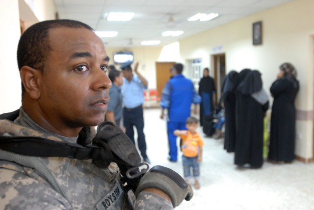 TAJI, Iraq- Norfolk, Va. Native, 1st. Lt. Alton Royster, the medical officer for the 1st Battalion, 82nd Field Artillery Regiment, watches as hospital staff interact with patients during a visit to the Taji Market Clinic, Sept. 27. The small clinic s...