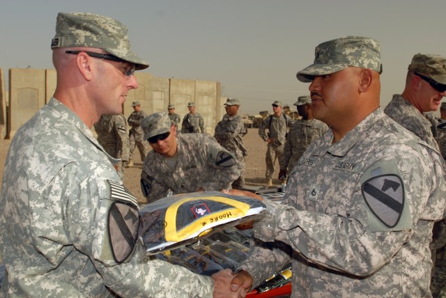 CAMP Taji, Iraq - Lt. Col. Eric Schwegler (left), of Ozark, Ala., commander of the 1st Battalion, 82nd Field Artillery Regiment, 1st Brigade Combat Team, 1st Cavalry Division, presents Pfc. Craig Flores, of Vallejo, Calif., an "Ironhorse" Brigade...