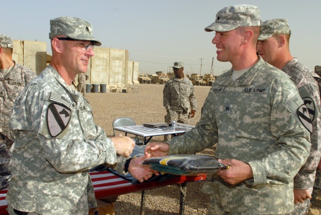 CAMP TAJI, Iraq - Lt. Col. Eric Schwegler (left), of Ozark, Ala., presents an "Ironhorse" Brigade jersey to Sgt. James Brown of Binghampton, N.Y. Schwegler is commander of the 1st Battalion, 82nd Field Artillery Regiment, 1st Brigade Combat Team,...