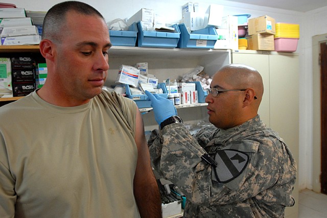 BAGHDAD - Spc. Armando Reyes (left), a health care specialist  from San Antonio, gives a flu shot to Staff Sgt. John Buchanan,  of Phoenix City, Ala., at the Battalion Aid Station, on Camp Liberty, Oct. 1.  "This flu shot is good for one year," said ...