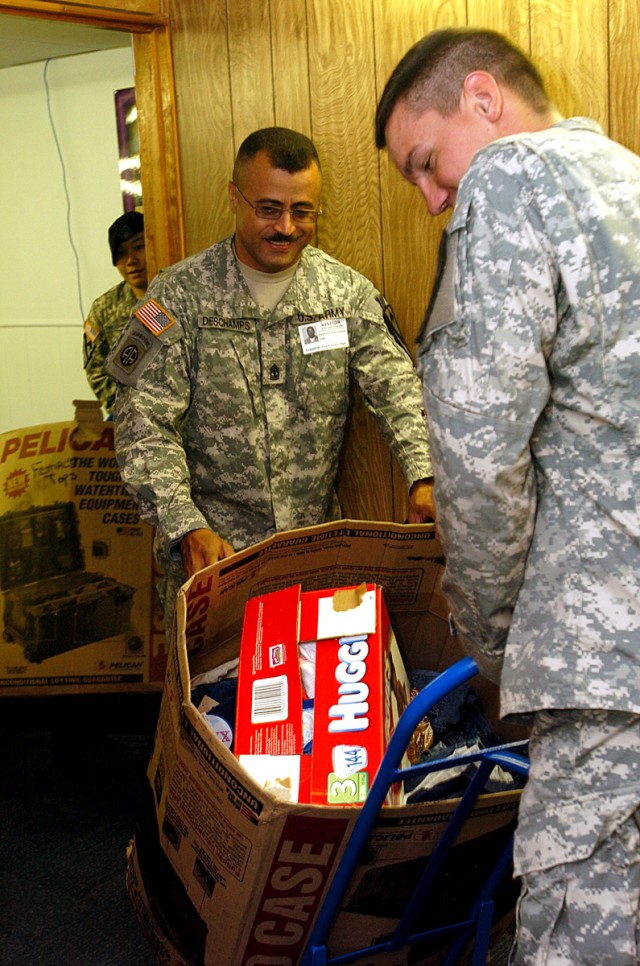 1st Battalion, 227th Aviation Regiment, 1st Air Cavalry Brigade, 1st Cavalry Division's 1st Sgt. Palermo Deschamps (left), of the Bronx, N.Y. and Spc. William Colley, of College Station, Texas, bring a box of clothes to Copperas Cove Jr. High...