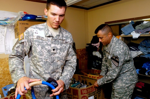 1st Battalion, 227th Aviation Regiment, 1st Air Cavalry Brigade, 1st Cavalry Division's 1st Sgt. Palermo Deschamps (right), of the Bronx, N.Y. and Spc. William Colley, of College Station, Texas, bring a box of clothes to Copperas Cove Jr. High...