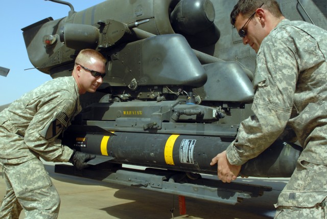 CAMP TAJI, Iraq - Spc. Sean McConnell (left), of Columbus, Ohio, and Spc. Scott Shaver, of Austin, Texas, load a Hellfire missile onto the mounting bracket on an AH-64D Apache helicopter, here, Oct. 1. Both Soldiers are armament electrical...