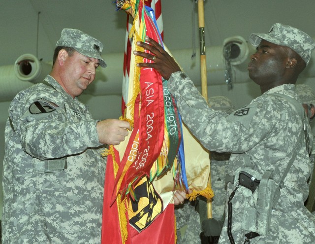 Col. Larry Phelps, 15th Sustainment Brigade commander, and Command Sgt. Maj. Nathaniel Bartee, 15th SB senior noncommissioned officer, uncase their unit's guidon in the Morale, Welfare and Recreation building here Oct. 5 as part of a transfer of...