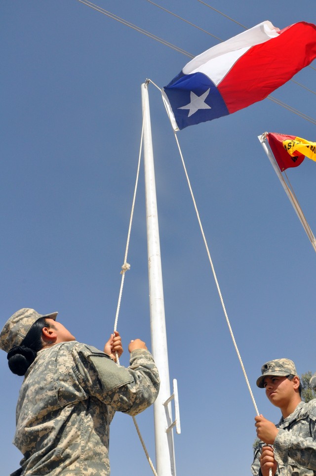 Pfc. Malorie Cano (left), 15th Sustainment Brigade supply specialist, and Spc. Liz Rivera, 15th SB wheeled vehicle mechanic, raise the Texas state flag in front of the brigade headquarters here Oct. 5 only minutes after a transfer of authority...