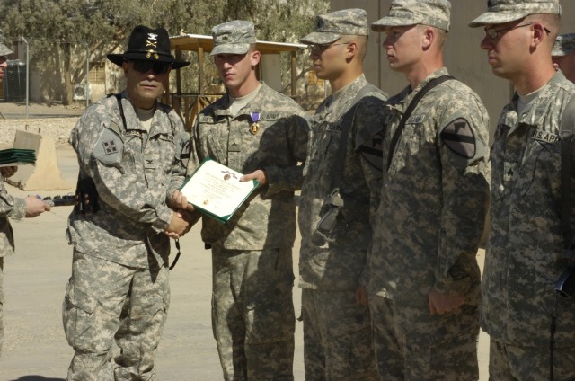 Col. Ryan Gonsalves, brigade commander of the 2nd "Black Jack" Brigade Combat Team, 1st Cavalry Division, shakes hands with Cpl. Adam Seiffert, a gunner of 1st Platoon, Blackhawk Troop, 4th Squadron, 9th Cavalry Regiment, after presenting him a ...