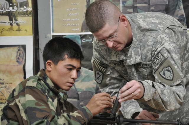 KANDAHAR AIRFIELD, Afghanistan - Capt. Jeff Whitten, the 286th Combat SupportSustainment Battalion headquarters and headquarters company commander, shows an Afghan National Army soldier how to reassemble an M-16 rifle during rifle training. Whitten, ...