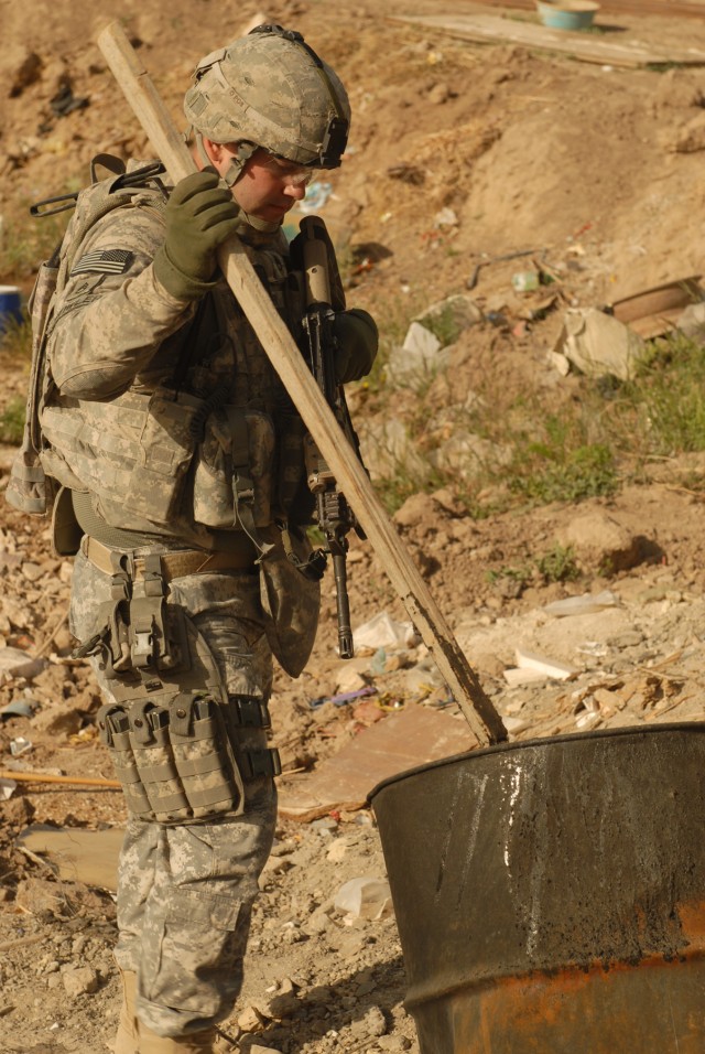 TAJI, Iraq - Staff Sgt. Shad Fowler, of Amarillo, Texas, looks inside a barrel while searching through a garbage pile on a joint patrol with the Iraqi Army near TajiOct. 5. Fowler is a light-wheel vehicle mechanic assigned to Company A, 1st...