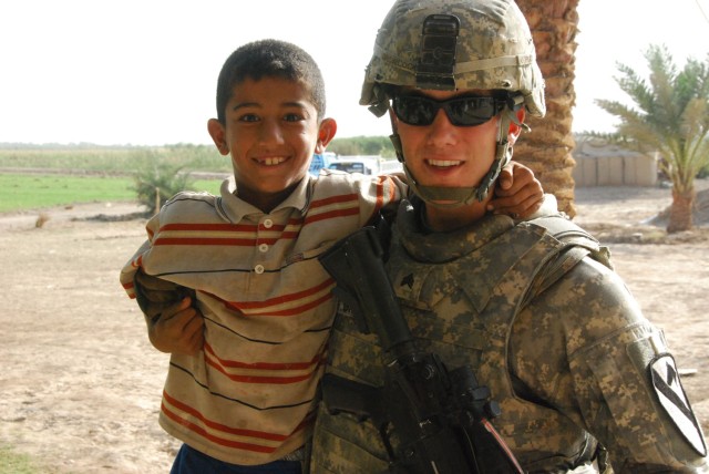 TAJI, Iraq- Winnemucca, Nev. native, Sgt. Buck Growcock, a squad leader assigned to the 1st Battalion, 82nd Field Artillery Regiment, 1st Brigade Combat Team, 1st Cavalry Division, poses for a picture with one of Sheik Abdullah's grandchildren,...