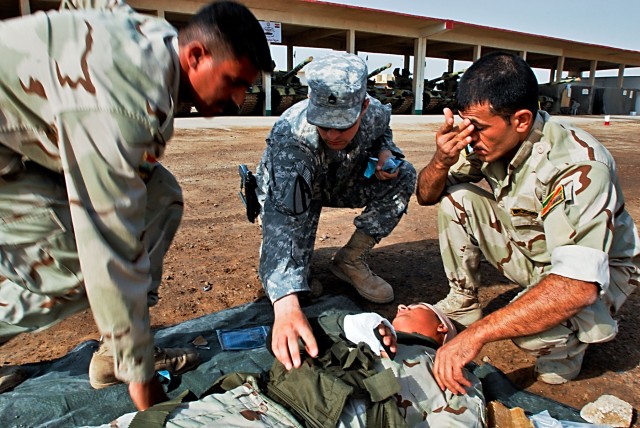 CAMP TAJI, Iraq-Staff Sgt. Matthew Kolakowski (center), from Lakewood, Wis., the brigade's surgeon noncommissioned officer in charge, 1st Air Cavalry Brigade, 1st Cavalry Division, displays how to correctly wrap a bandage on an abdominal wound to Sol...