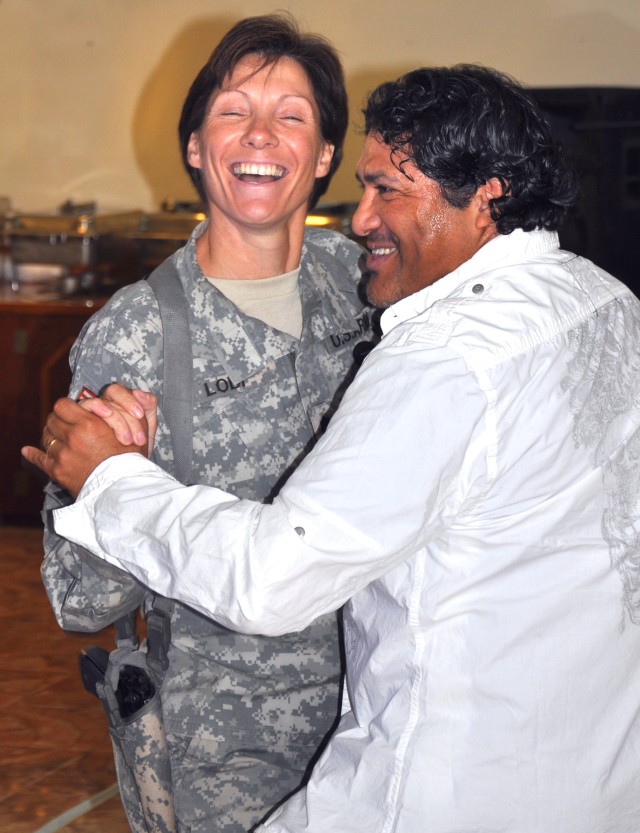 Lt. Col. Paula Lodi, commander 15th Special Troops Battalion, 15th Sustainment Brigade, dances with Alex Cruz, logistics warehouse contractor and Salsa dance instructor, at a Hispanic Heritage month luncheon at the main dining facility here Oct. 10. ...