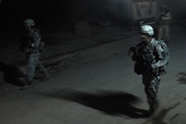 BAGHDAD - Sgt. Robert Willard (right), a tanker from Pulaski, Va., assigned to Company C, 2nd Battalion, 5th Cavalry Regiment, 1st Brigade Combat Team, 1st Cavalry Division, walks the dark streets of eastern Baghdad with his IA counterparts during...