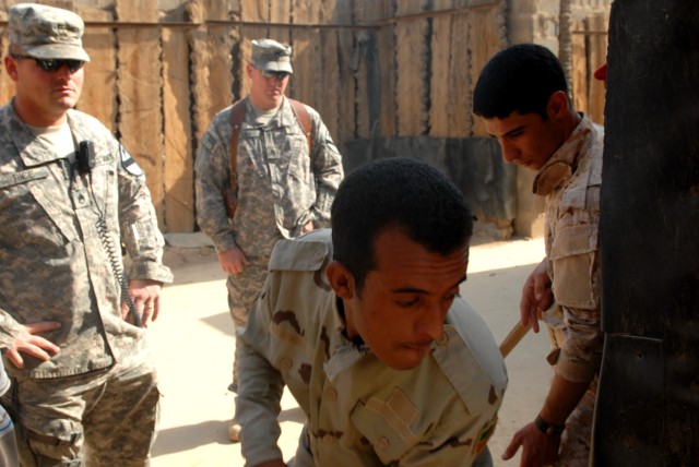 BAGHDAD - Staff Sgt. Dustin Rice (left), from St. Paul, Neb., and Staff Sgt. Kirk High (background right), from Fort Worth, Texas, both course instructors, watch Iraqi Army Soldiers enter a doorway during a mock-room clearing exercise at Joint...