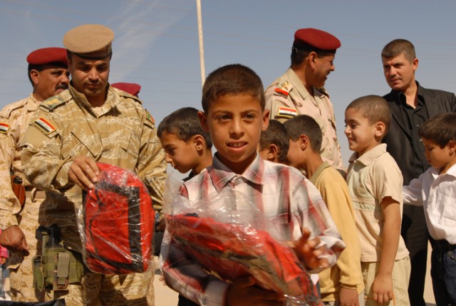 Children receive backpacks from Iraqi Army soldiers in the 1st Battalion, 15th Iraqi Army Brigade, 12th Iraqi Army Division, during a Junior Hero Program at their school in Arab Koy in Kirkuk province, Iraq, Oct. 20. Children also recited a pledge to...