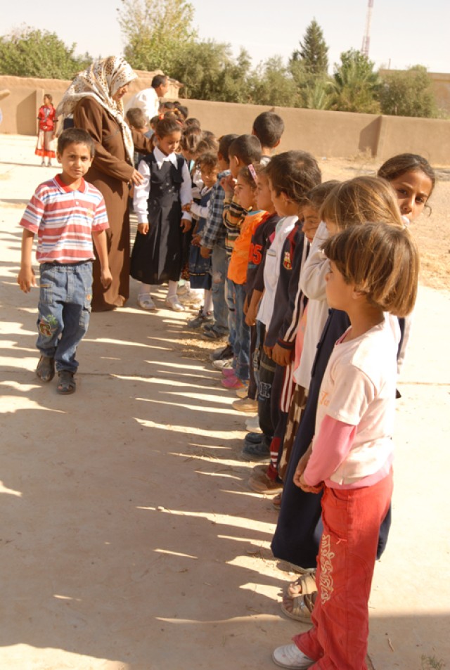 Children at a school in Arab Koy in Kirkuk province, Iraq, prepare to receive backpacks during a Junior Hero Program at their school Oct. 20. Before receiving the backpacks, the children recited a pledge to become Junior Heroes in their community and...
