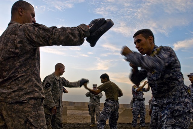 BAGHDAD - Iraqi Federal Policemen hone their punching techniques, assisted by Staff Sgt. David Free (foreground), from Hull, Ga., and Spc. Robert McDaniel (background), from Memphis, Tenn. during hand-to-hand combat training at Joint Security Station...