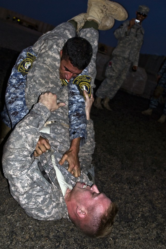 BAGHDAD - Sgt. Thomas Robbins (bottom), from Birmingham, Ala., grapples with an Iraqi Federal Policeman during hand-to-hand combat training at Joint Security Station Istaqlal, here, Oct. 20. The FP is attempting to "arrest" Robbins, who is resisting ...