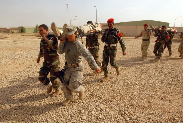 Staff Sgt. Monnet Bushner, from Humble, Texas, and a medic with the 218th Military Police Company from Fort Campbell, Ky., demonstrates how to carry a casualty on a stretcher with Iraqi military police from the 12th Iraqi Army Division, at K1...
