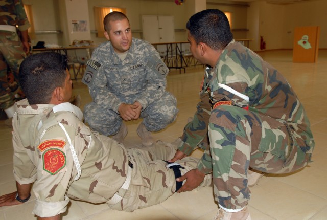 Pvt. Keith O'Connell, from Lawler, Iowa, and a medic with the 218th Military Police Company from Fort Campbell, Ky., instructs Iraqi military policemen from the 12th Iraqi Army Division on how to apply tourniquets, emergency trauma bandages,...