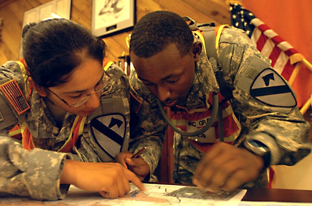 Spcs. Victoria Caldera (left) and Marcus Gray, of Company D, Forward Support Battalion, 1st Squadron, 9th Cavalry Regiment, 4th BCT, 1st Cav. Div., work together to plot their points before heading out to the land navigation site Oct. 21, during...