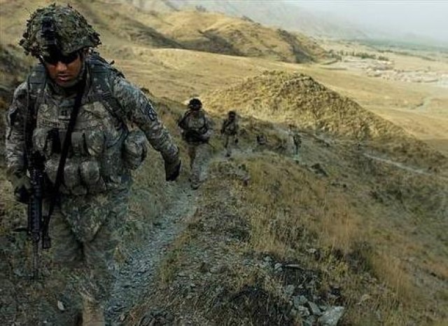 Soldiers in full battle gear travel a mountain trail in Afghanistan.