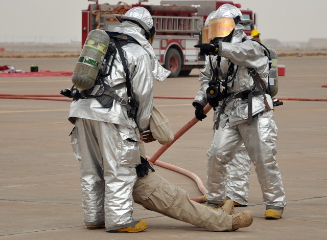 A Q-West firefighter gives direction while another holds a man who role played a fleeing delusional victim of a simulated helicopter crash during a mass casualty exercise here Oct. 28. (U.S. Army photo by Sgt. Matthew C. Cooley, 15th Sustainment Brig...