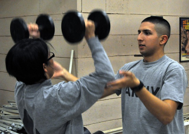 Sgt. Mike Martin, a Las Vegas native and ammo supply sergeant spots Staff Sgt. Sabrina Barragan, 15th Sus. Bde. ammo supply sergeant and Brownsville, Texas, native during part of a CrossFit training session in the new Headquarters and...
