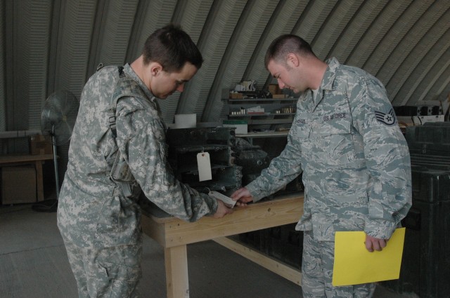 Spc. Michael Salata, a unit supply specialist with C Company, 84th Engineers, 130th Engineer Brigade, and Air Force Staff Sgt. Todd Michael, a turn-in section specialist, with the 402nd Army Field Support Brigade, inspect items at the Contingency Ope...