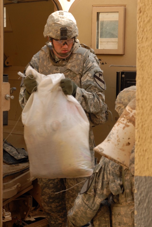 Pfc. Devin Brown, a Dallas, Ga., native and a cannon crew member with 3rd Battalion, 82nd Field Artillery Regiment, 2nd Brigade Combat Team, 1st Cavalry Division, helps unload bags of food and household goods during a humanitarian aid delivery in the...