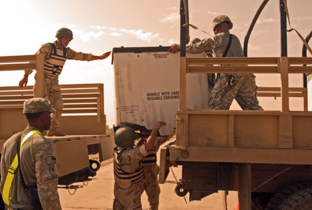 Soldiers with the 12th MTR, 12th IAD, transfer cargo from one truck to another as a U.S. Army Soldiers watch their performance during a competition at K-1 Military Base in Kirkuk, Nov. 1. This was a chance for the IA soldiers to test their skills...