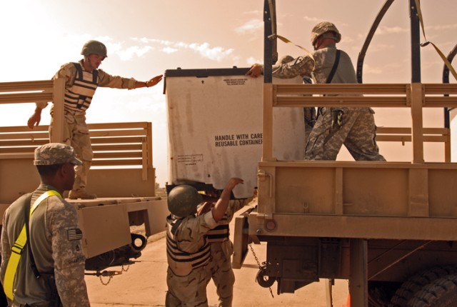 Soldiers with the 12th MTR, 12th IAD, transfer cargo from one truck to another as a U.S. Army Soldiers watch their performance during a competition at K-1 Military Base in Kirkuk, Nov. 1. This was a chance for the IA soldiers to test their skills as ...