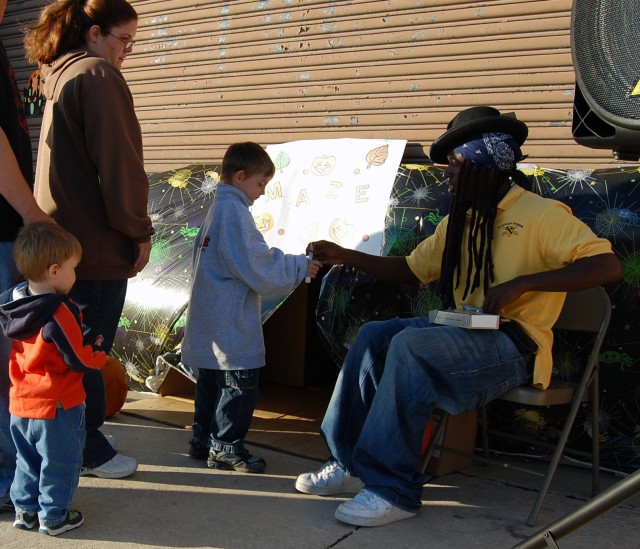 A Soldier assigned to the 2nd Battalion, 12th Cavalry Regiment, 4th Brigade Combat Team, 1st Cavalry Division, gives a neon glow stick to one of the children preparing to enter a Halloween Maze during the 2nd Annual Trick-or-Trunk Event at the...