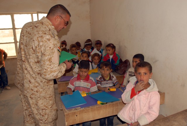 Second Lieutenant Abdul Hadi Faisal, an Iraqi officer with the 46th IA Bde., helps distribute school supplies to Iraqi children at the Jadeeda Primary School near Hawijah in the Kirkuk province of Iraq, Oct. 28. The supplies were provided by Families...