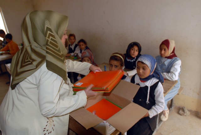 An Iraqi school teacher helps distribute school supplies to Iraqi children at the Jadeeda Primary School near Hawijah in the Kirkuk province of Iraq, Oct. 28. The supplies were provided by Families of Soldiers Families of Soldiers from 1/8th Cav., 2B...