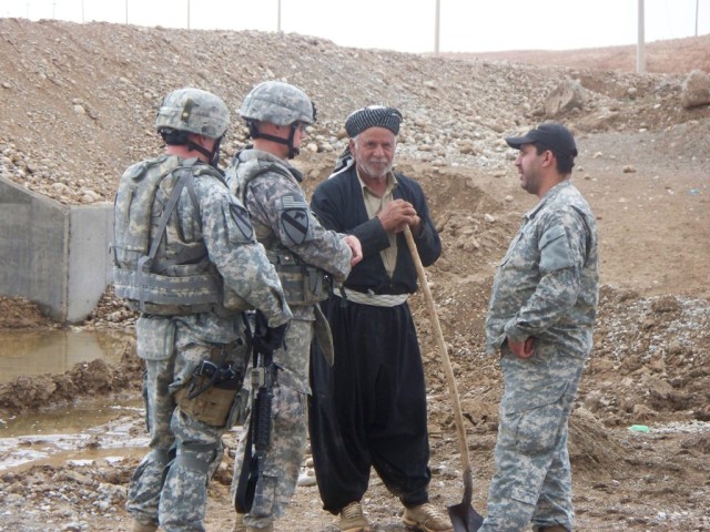 Regiment, 2nd Brigade Combat Team, 1st Cavalry Division, speaks with a resident of Bidawa in Kirkuk province, Iraq, in front of a new culvert in the village, Oct. 7. These new culverts will ease the flow of traffic in the village and allow water to f...