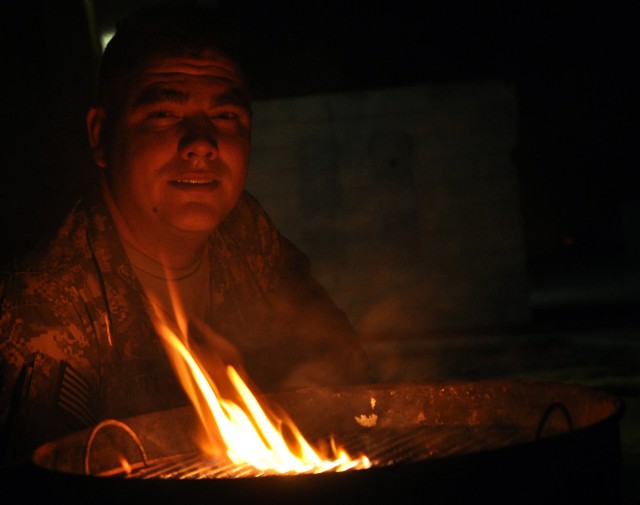 Spc. Jason Grady, a North Glenn, Colo., native and 15th Special Troops Battalion, 15th Sustainment Brigade, supply specialist, watches a flame after lighting a grill at the battalion's headquarters here Oct. 30 as part of a unit movie night. Soldiers...