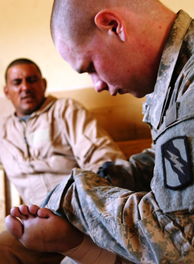 CONTINGENCY OPERATING LOCATION Q-WEST, Iraq - Pfc. Michael J. Slemensky, a Hernando, Miss., medic with 1st Platoon, A Company, 2nd Battalion, 198th Combined Arms also from Hernando, applies a pressure bandage to Cpl. Raad Hussein, a member of 1st Com...