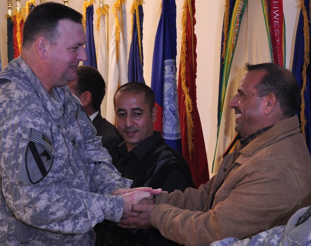 Col. Larry Phelps, the 15th Sustainment Brigade commander, gives a coin to pump foreman Abdullah Ahmed from the Al-Qayyarah pump house at luncheon in pump house workers' honor in the dining facility here, Nov. 3. (U.S. Army photo by Sgt. Matthew...
