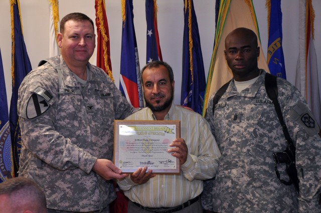 Col. Larry Phelps, the 15th Sustainment Brigade commander, and Command Sgt. Maj. Nathaniel Bartee, the 15th Sust. Bde. senior noncommissioned officer, thank the Al-Qayyarah pump house workers with a plaque presented to Naif Dhahy, the pump house...
