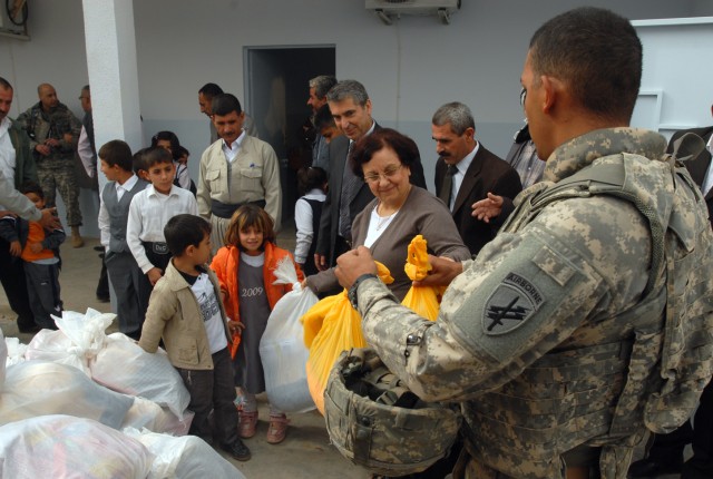 First Lieutenant Samil Reyes (right), a Fayetteville, N.C., native and civil affairs team leader with the 414th Civil Affairs Company, assists Iraqi Deputy Director General of Education Fawzia Abdullah Awanis, in distributing school supplies and...