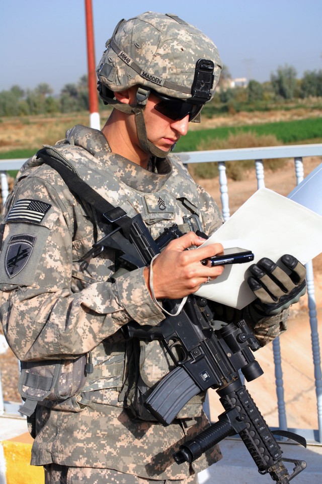 TAJI, Iraq - Cambridge, Mass. native, Staff Sgt. Carlos Madden, a civil affairs team leader assigned to 1379th Civil Affairs Company, uses a public works contract to inspect the Sheik Abdullah Bridge in Taji, Nov. 10. The bridge is a civil...