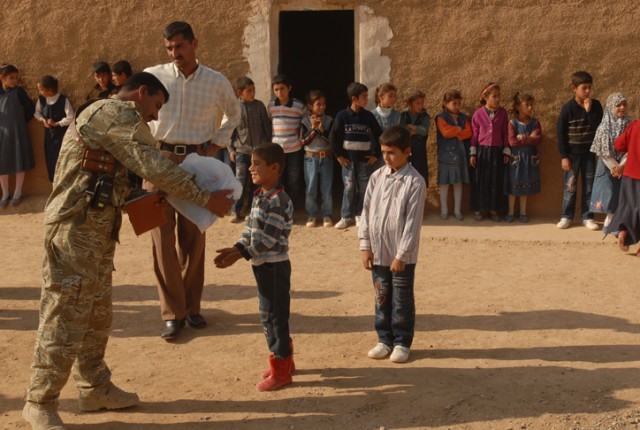An Iraqi Army officer gives school supplies to a smiling child in the village of Abu Shahab in Kirkuk province, Iraq, Nov. 9. Although scared of all the soldiers at first, the children were soon happy to see them and happy to receive their new school...