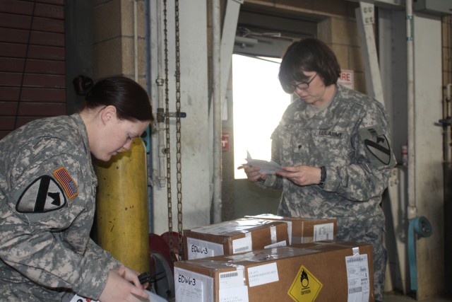 From left to right: Spc. Jennifer Welfe, assigned to the 4th Brigade Combat Team, 1st Cavalry Division "Long Knives" from Reno, Nevada and Spc. Venessa Cross from Pittsfield, Mass., inspect a shipment of new medical equipment during a process the...