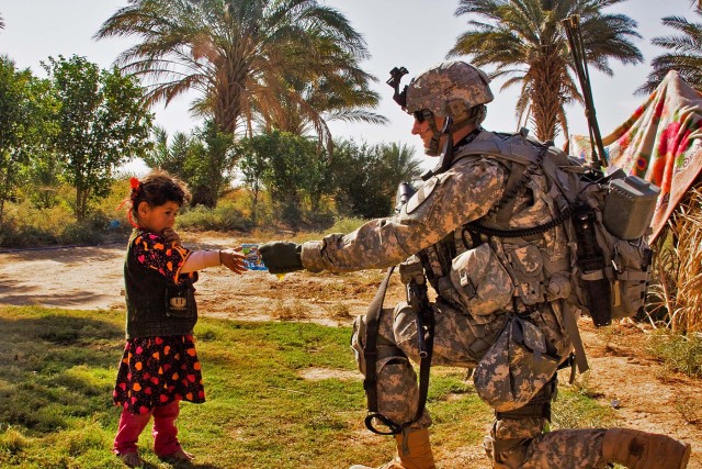 TAJI, Iraq-1st Lt. Austin Huckabee, from San Angelo, Texas, hands a small bag of candy to a young Iraqi girl during a patrol in a small village north of Taji, Iraq, Nov. 12. American Soldiers and the 34th Iraqi Army Brigade performed a joint air...