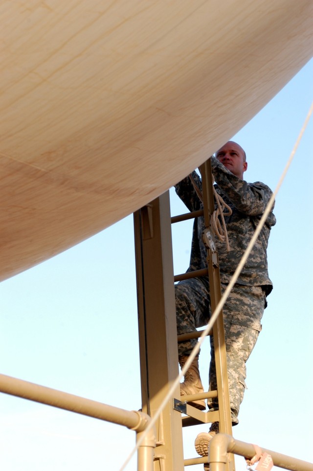 CONTINGENCY OPERATING LOCATION Q-WEST, Iraq - Staff Sgt. John W. Pidgette (left), noncommissioned officer-in-charge and native of Horn Lake, Miss., climbs the mooring station's tower ladder of Q-West's 17-meter Aerostat to examine the balloon's...
