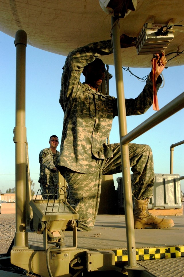 CONTINGENCY OPERATING LOCATION Q-WEST, Iraq - Aerostat crewmember Spc. Andrew N. Faulkner (right, rear) from Hernando, Miss., mans the winch control panel as Pfc. Alex G. Anthony, a crewmember from Memphis, Tenn., inspects the ARDD installation,...