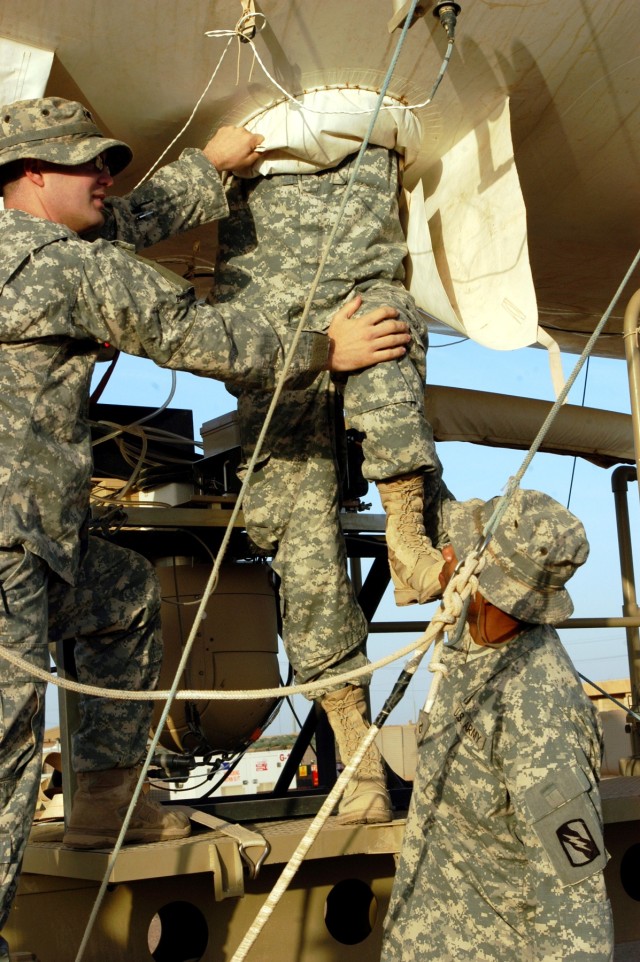 CONTINGENCY OPERATING LOCATION Q-WEST, Iraq - Spc. Andrew N. Faulkner (left) from Hernando, Miss., and Pfc. Alex G. Anthony (lower right) from Memphis, Tenn., both aerostat camera technicians, steady Staff Sgt. John W. Pidgette, noncommissioned...